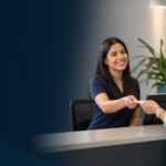 Recepcionista atendendo visitante em balcao de atendimento